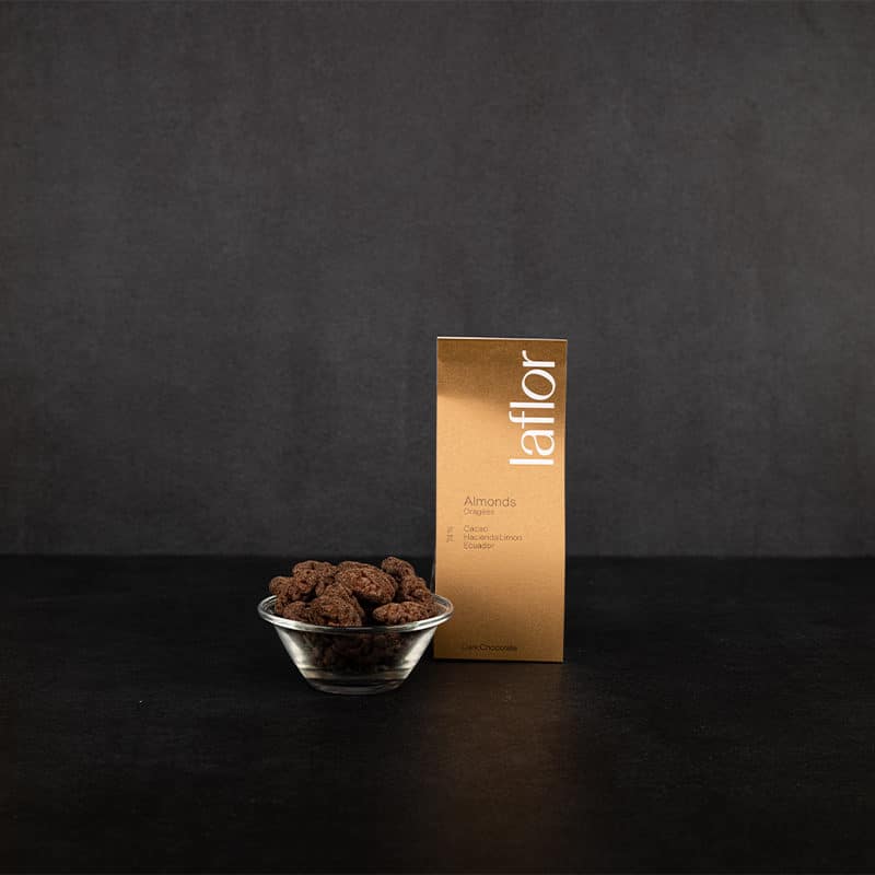 Mit Schokolade umhüllte Mandeln in edler Verpackung und offen in kleiner Glasschale