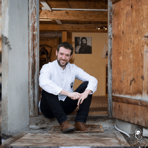 Adrian Hirt sitzt im Hauseingang auf der Treppenstufe und im Hintergrund sieht man seinen Urneni auf einem Bild