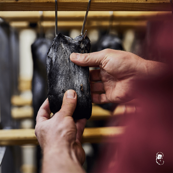 Zwei Hände tasten aufgehängtes Trockenfleisch