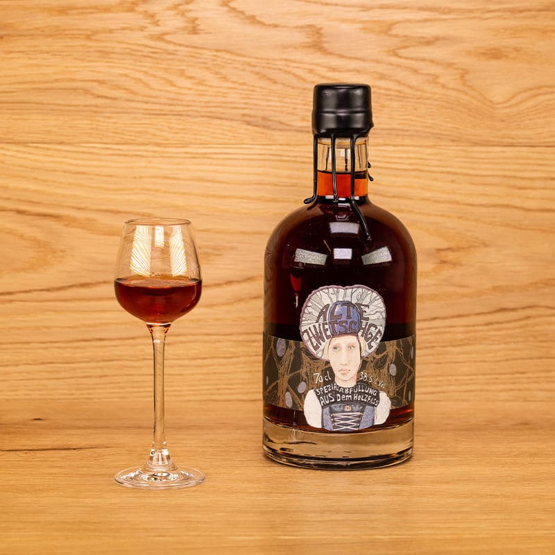 Alte Zwetschge mit dekorativer Etikette und Wachsverschluss mit eingeschenktem Glas