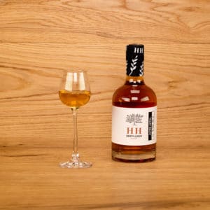 Alter Apfel in dekorativer Flasche mit eingeschenktem Schnapsglas