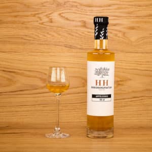 Apfelessig in Flasche mit eingeschenktem Glas