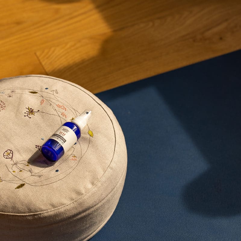 Moodbild von Aromaspray Frühling auf einem grauen Sitzkissen auf einer blauen Yogamatte