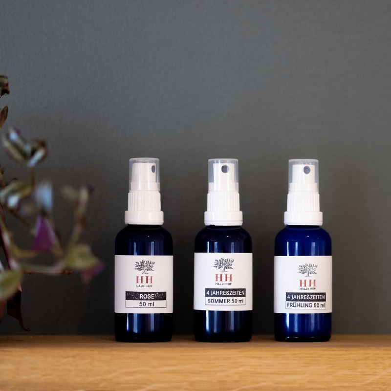 Moodbild von allen drei Sorten Aromasprays auf einem Holzuntergrund. Daneben steht eine Pflanze.