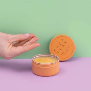Body Butter mit Hand vor farbigem Hintergrund
