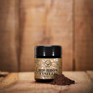 gemahlene Bourbon Vanille in Mironglas auf Holzhintergrund