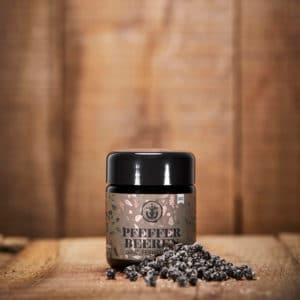 Fermentierte Pfefferbeeren im Mironglas und davor auf dem Tisch ausgelegt