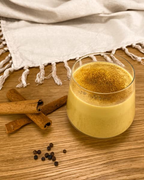 Kurkuma Latte Moodbild mit Zimtstangen und Pfefferkörner