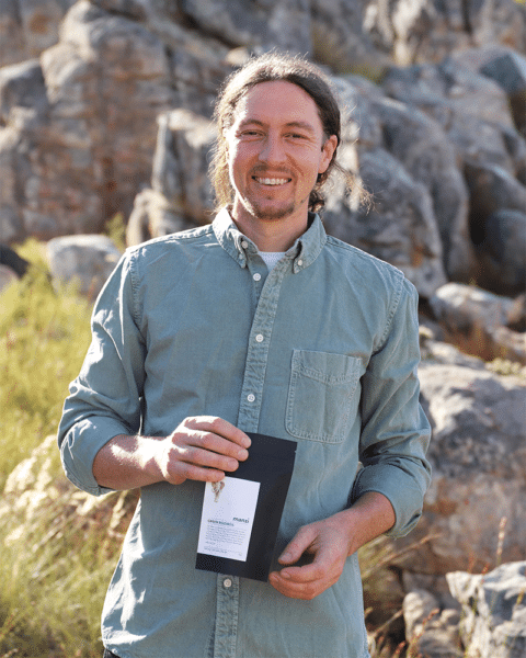 Teammitglied von Manzi in den Südafrikanischen Bergen mit Rooibos Tee in der Hand