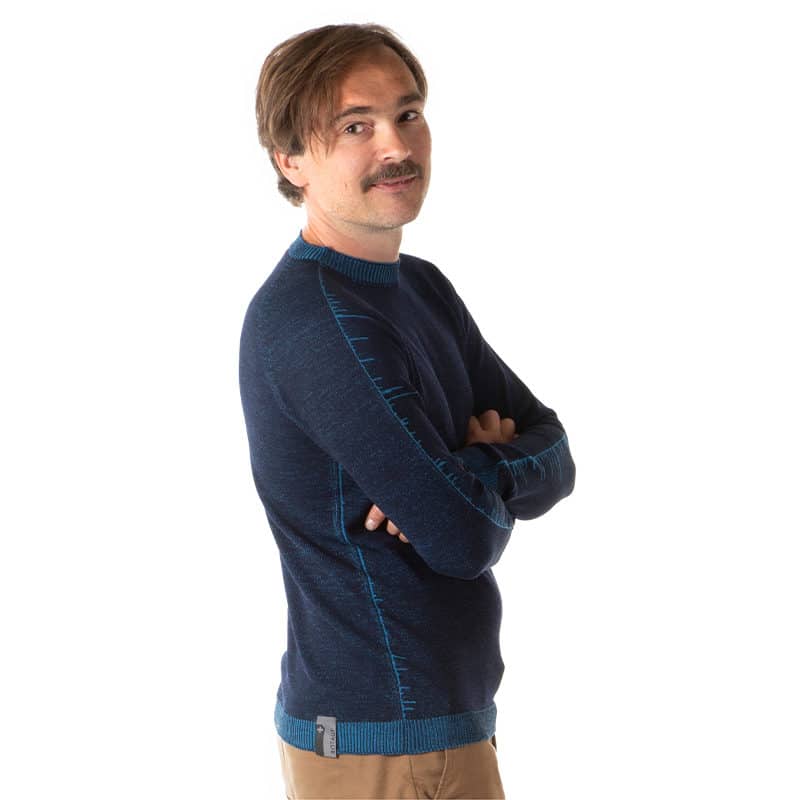 Mann trägt blauen Merinopullvoer von Rotauf und lächelt