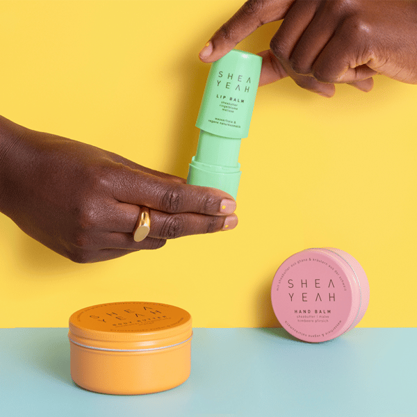 Shea Yeah Produkte mit Händen vor farbigem Hintergrund