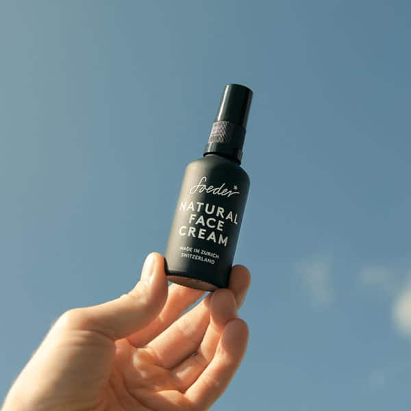 Soeder Gesichtscreme die von einer Hand gehalten und in die Luft gestreckt wird