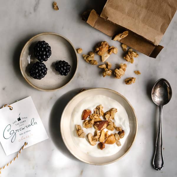 Granola mit Quark in Müslischale mit Früchten und Löffel daneben