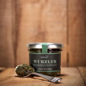 Wuzler Wildkräuter Würzpaste im Glas mit vollem Löffel davor