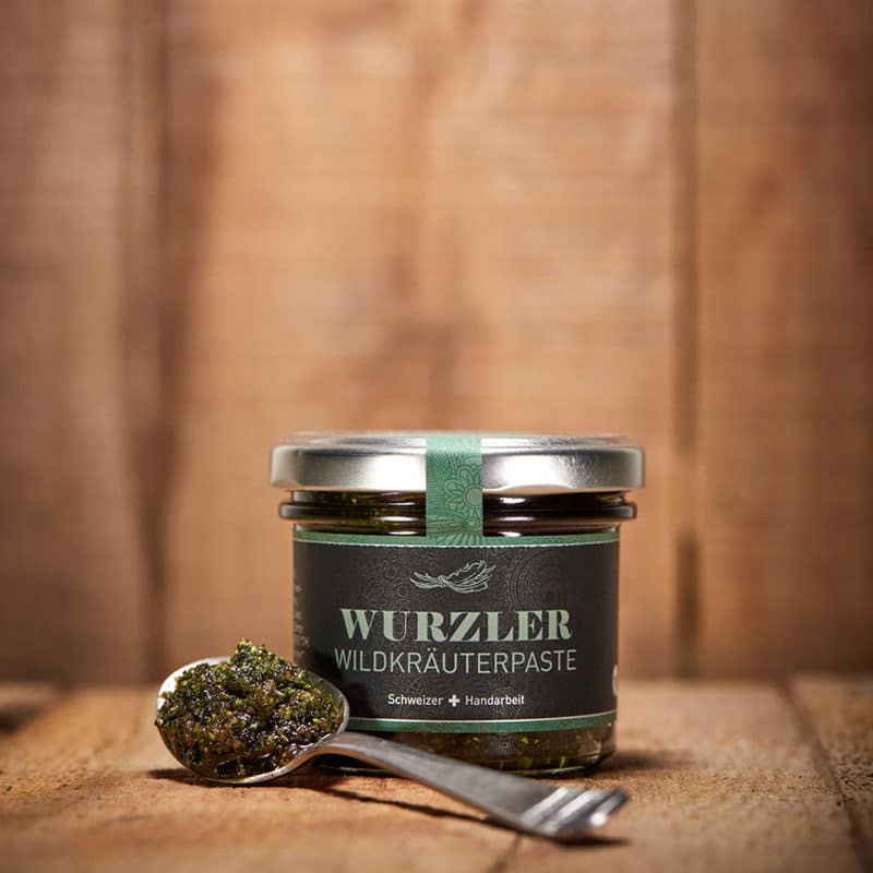 Wuzler Wildkräuter Würzpaste im Glas mit vollem Löffel davor