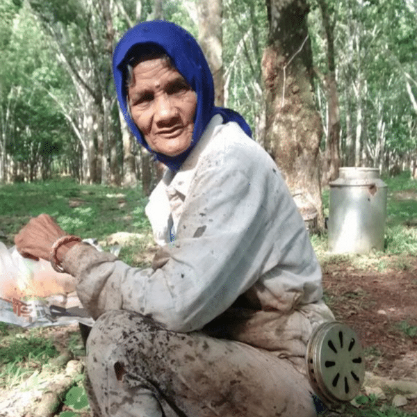 Eine einheimische Frau mitblauen Kopftuch und Leinen Kleider kniet am Boden.
