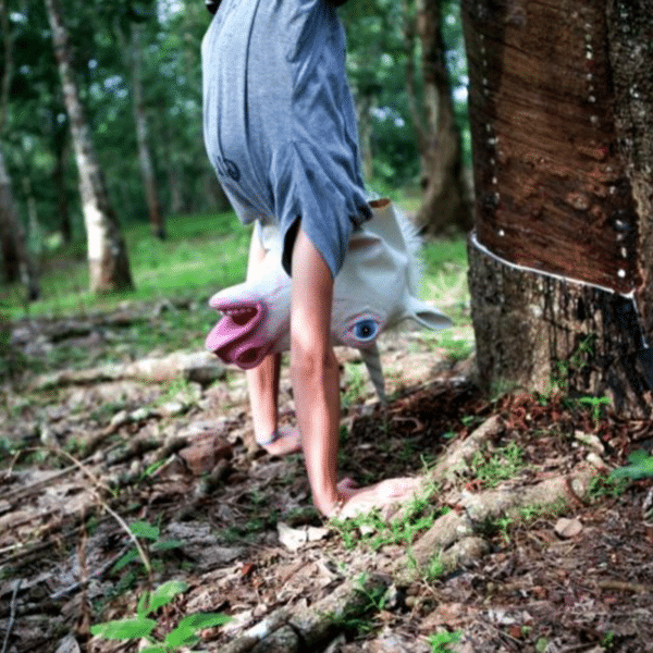Ein Mann mit einer Einhorn-Maske macht im Wald einen Handstand.