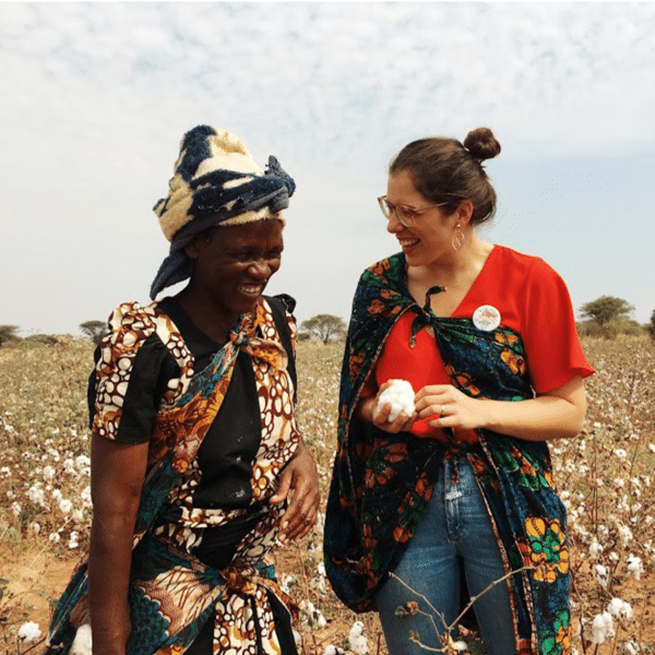 Zwei Frauen stehen auf einem Baumwollfell und lachen.